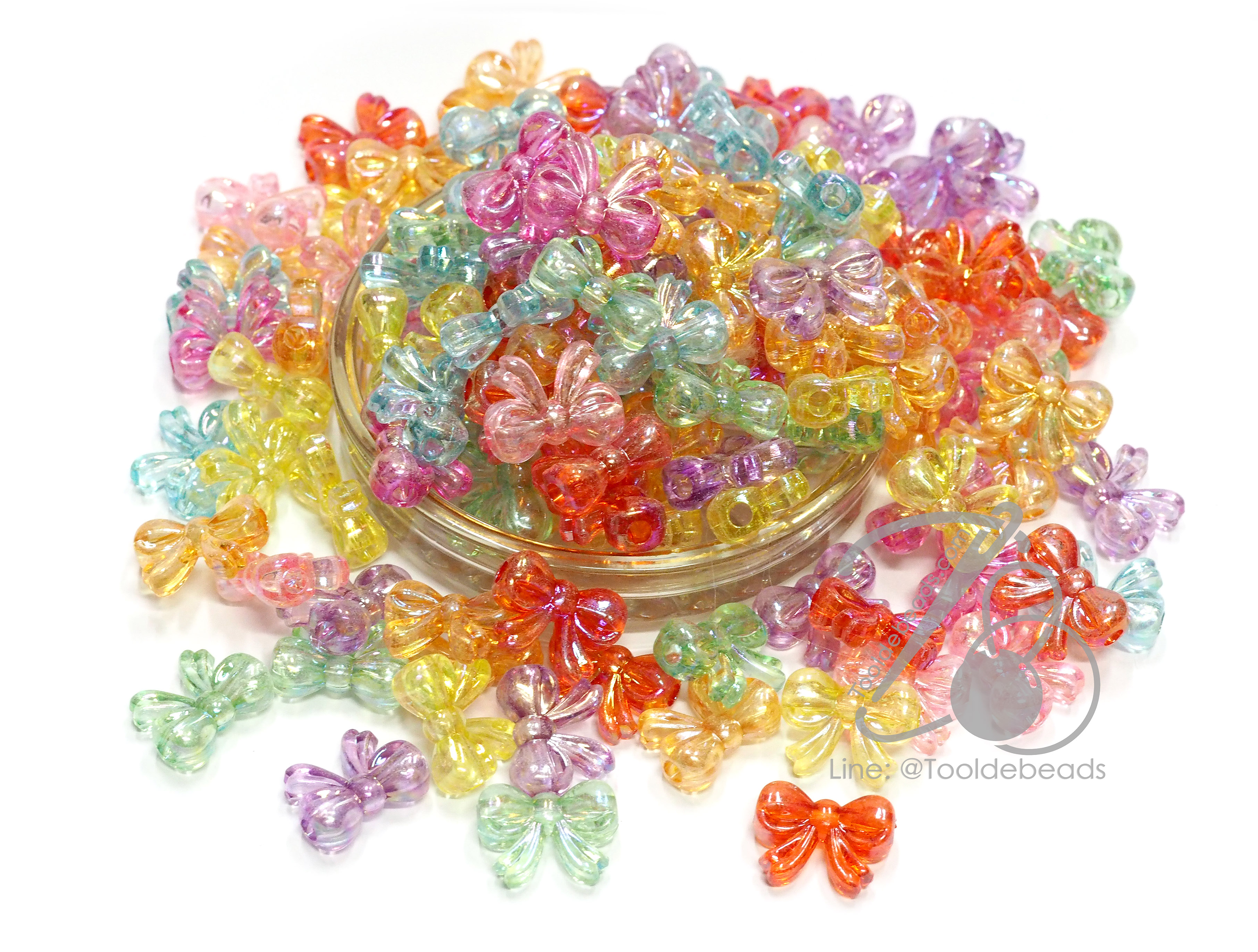 ลูกปัดพลาสติก เคลือบรุ้ง 12*20มม. ลายโบว์อ้วน คละสีรุ้งใส (100 กรัม) SKU-14476
